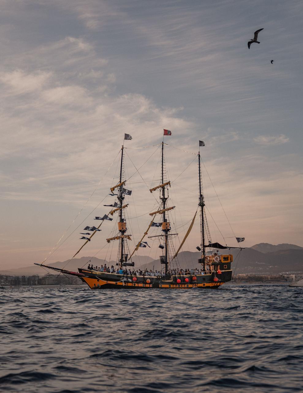 Velero turístico navegando frente a Cabo San Lucas al atardecer